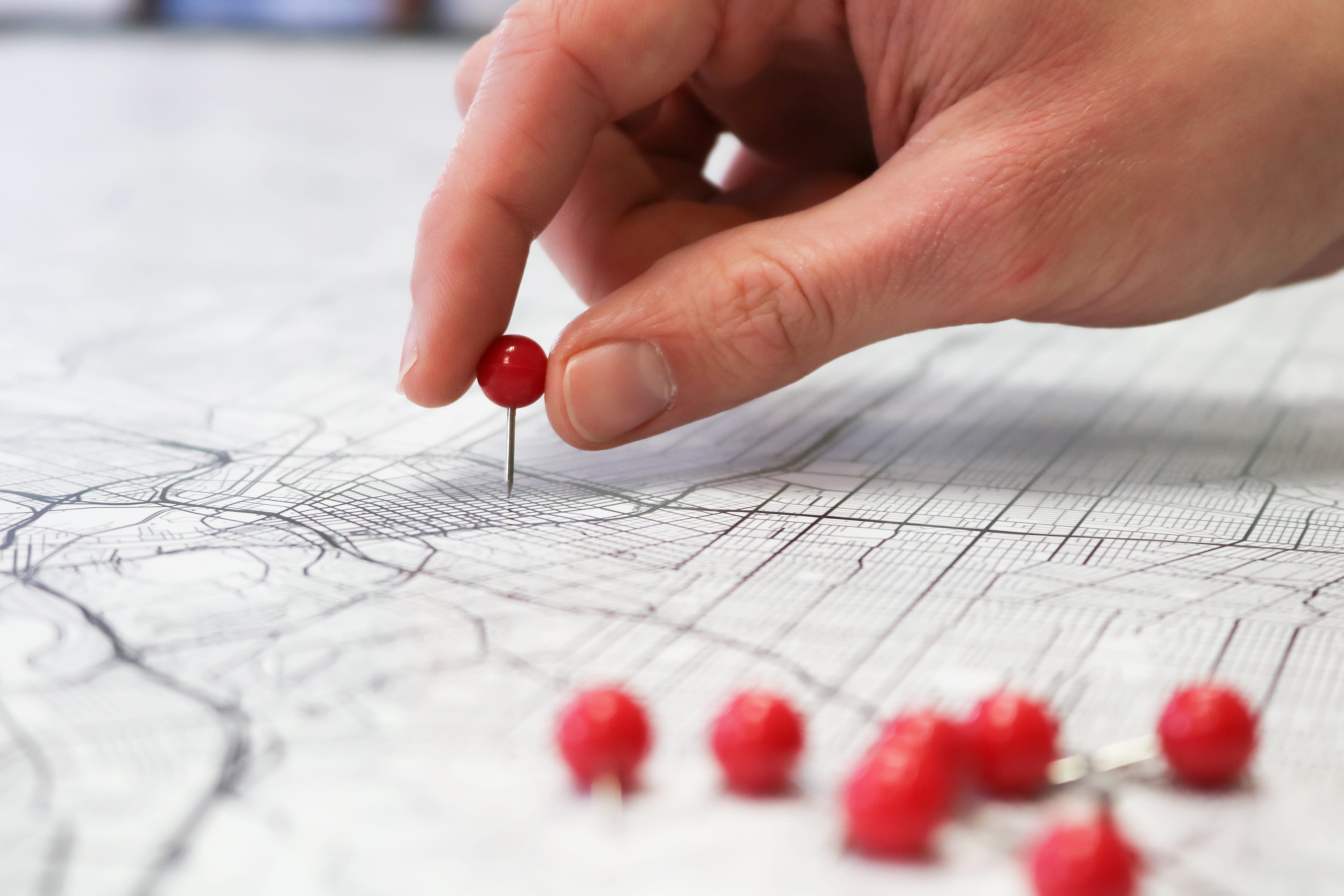 A hand placing a pin into a map to indicate a place on the map.