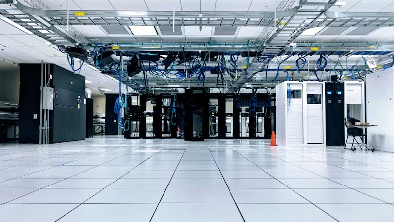 A server room with rows of black and white cabinets under blue cables